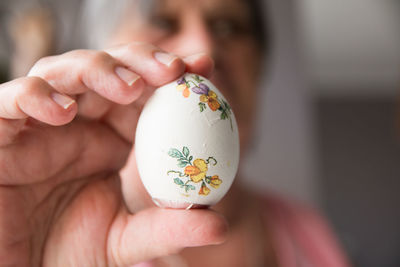 Close-up of woman holding egg with floral pattern