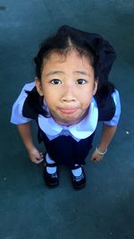 High angle portrait of cute school girl on road