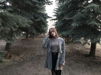 Portrait of young woman standing against trees