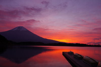 Scenic view of lake by mountains against sky during sunset