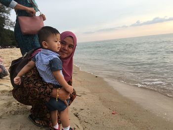 Full length of mother and daughter standing on beach