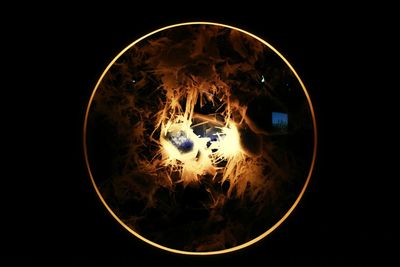 Close-up of illuminated lighting equipment against black background