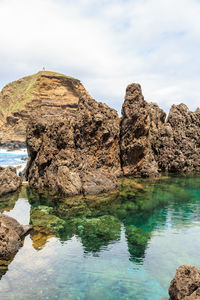 Rock formation by sea against sky