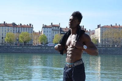 Full length of shirtless young woman standing against sky