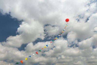 Low angle view of balloon flying against cloudy sky