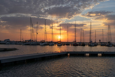 Sailboats moored at harbor during sunset