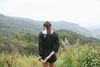 Rear view of woman standing on mountain against clear sky