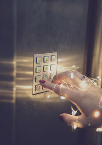 Close-up of woman with illuminated string lights pressing keypad