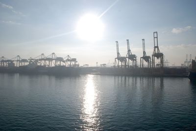 Cranes at harbor against sky