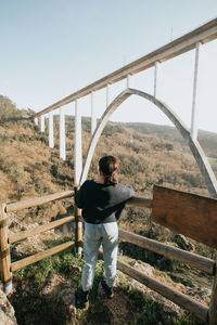 Rear view of man standing on bridge