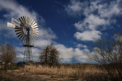 Low angle view of traditional windmill on field against sky