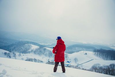 Rear view of woman standing on snow covered landscape