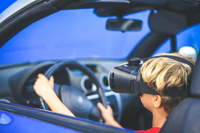 Boy wearing virtual reality simulator sitting in car