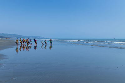 People at beach against clear sky