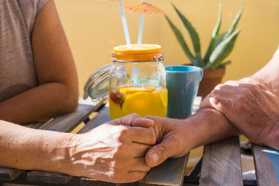 Close-up of couple holding hands on table at sidewalk cafe