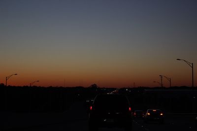 Cars on road against sky during sunset