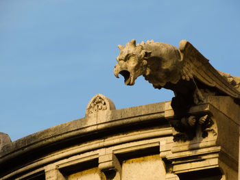 Low angle view of statue against historic building against clear sky