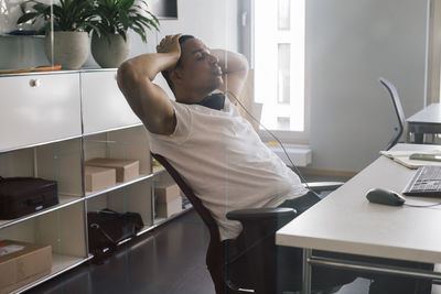 Overworked male entrepreneur with head in hand sitting on chair at office