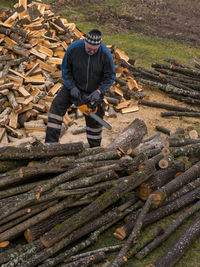 Full length of man sitting on log logs in forest