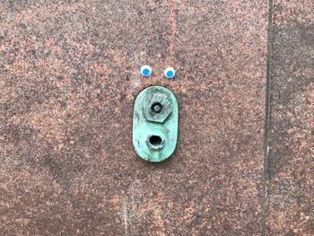 Close-up of blue googly eyes on textured wall