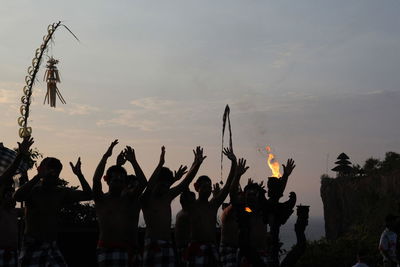 Tribal performing traditional dance against sky during sunset
