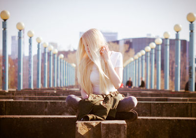 Full length of woman sitting on railing against sky