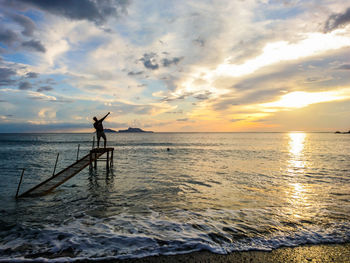 Silhouette person on beach against sky during sunset