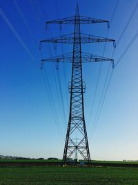 Low angle view of electricity pylon against blue sky