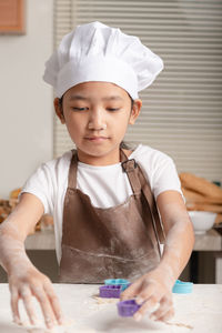 Portrait of cute boy preparing food in kitchen