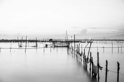 Wooden posts in sea against sky