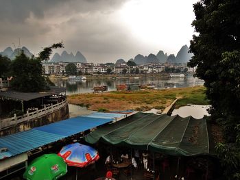 Buildings by river against sky in city