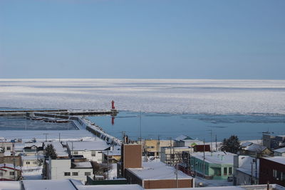 High angle view of buildings by sea against clear sky