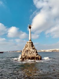 Lighthouse by sea against sky