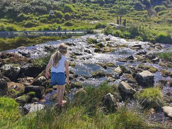 Rear view of little girl standing on rock