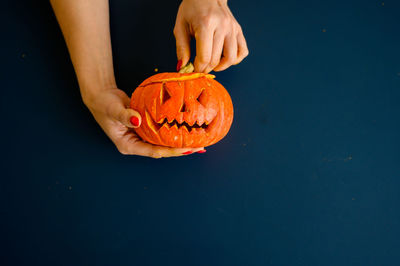 Midsection of person holding pumpkin against black background