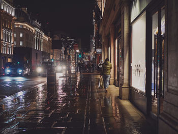 People walking on wet footpath in city during rainy season