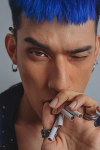 Close-up portrait of young man holding cigarettes