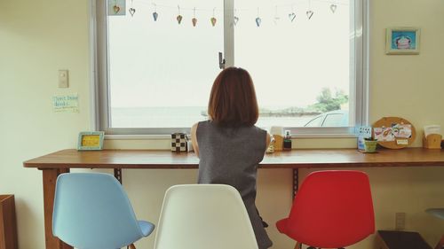 Rear view of woman sitting on chair at home