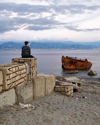 Rear view of man sitting on boat against sea