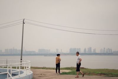 Rear view of people standing by cityscape against sky