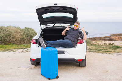 Rear view of man on boat at beach against sky