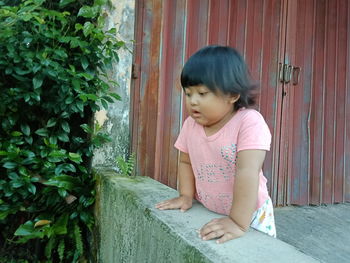 Full length of woman sitting against pink wall