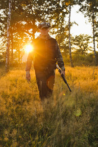 Hunter walking through field at sunset