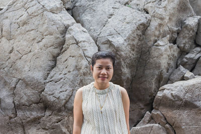 Portrait of smiling woman standing on rock formation 