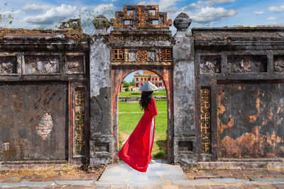 Rear view of woman standing against historic building