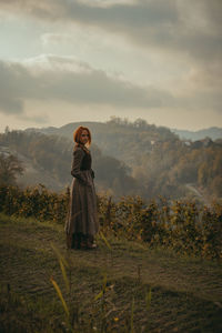 Rear view of woman standing on field against sky