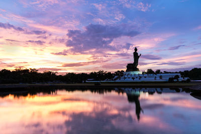 Reflection of statue in lake during sunset