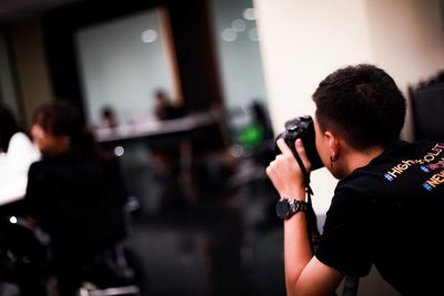 Man photographing through camera while sitting at restaurant