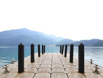 Wooden posts in sea against clear sky