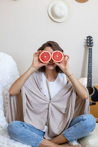 Portrait of a smiling girl holding fruit at home